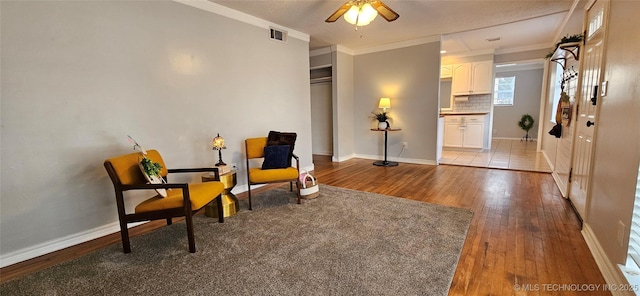 sitting room featuring ceiling fan, wood-type flooring, and crown molding