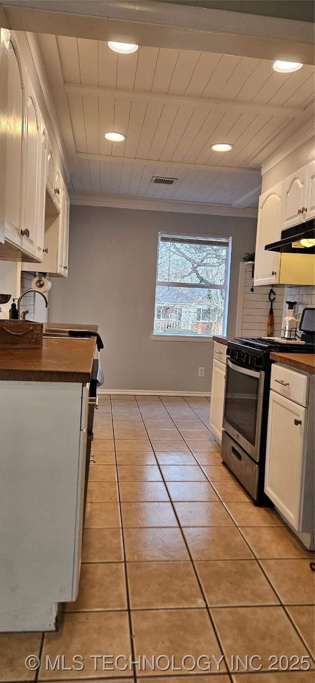 kitchen featuring light tile patterned floors, white cabinetry, stainless steel gas range, backsplash, and crown molding