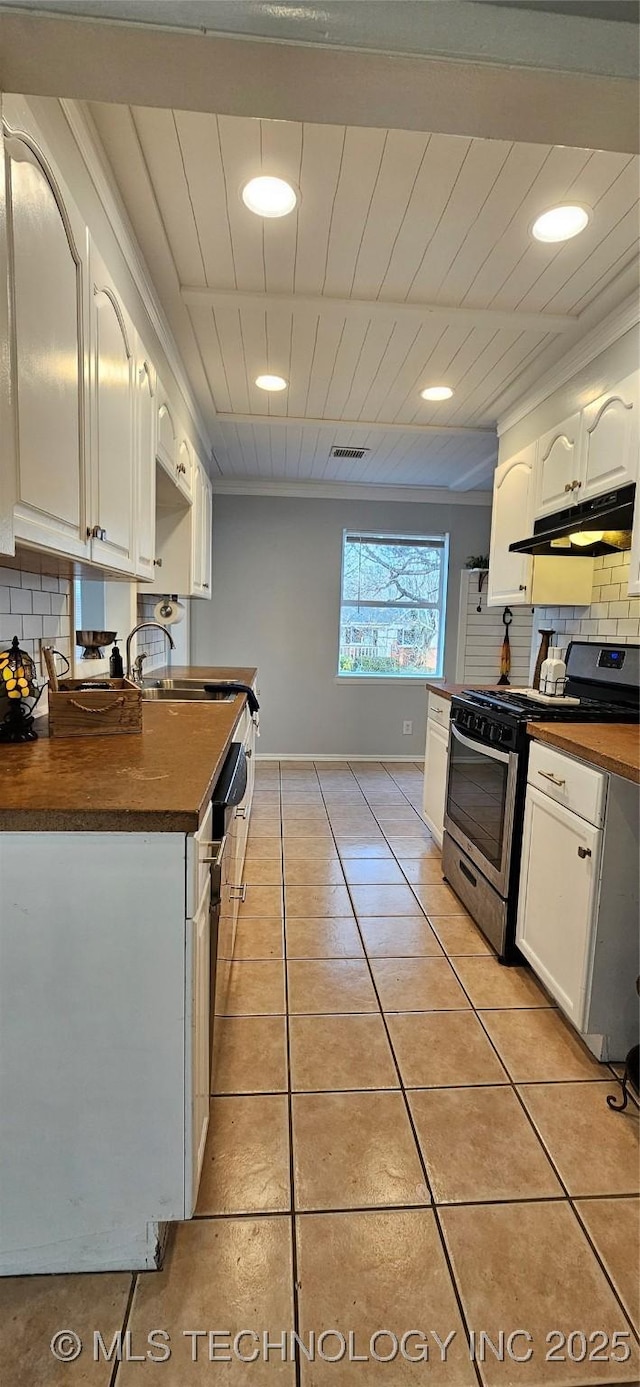 kitchen with light tile patterned floors, white cabinetry, stainless steel gas stove, and tasteful backsplash