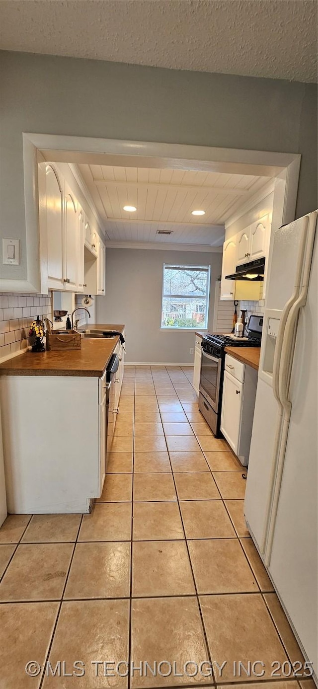 kitchen featuring wood counters, light tile patterned flooring, stainless steel stove, white cabinets, and white refrigerator with ice dispenser