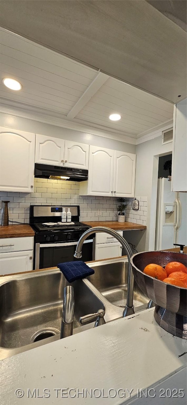 kitchen with gas range, backsplash, white fridge with ice dispenser, and white cabinets