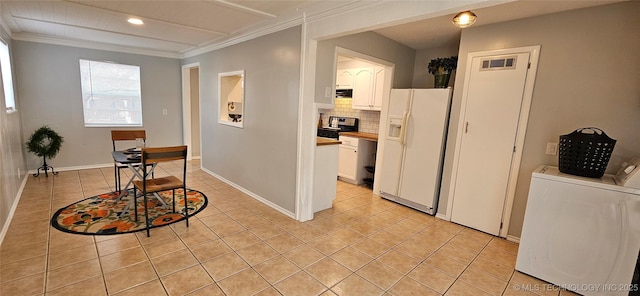 corridor featuring washing machine and clothes dryer, light tile patterned flooring, and ornamental molding