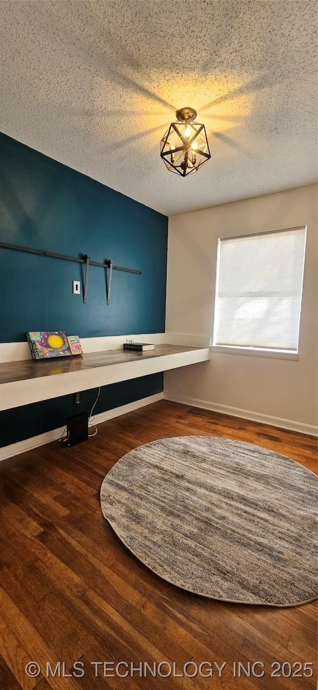 unfurnished bedroom featuring a chandelier, a textured ceiling, and hardwood / wood-style floors