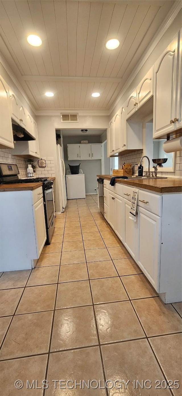 kitchen with light tile patterned floors, white cabinets, gas stove, and tasteful backsplash