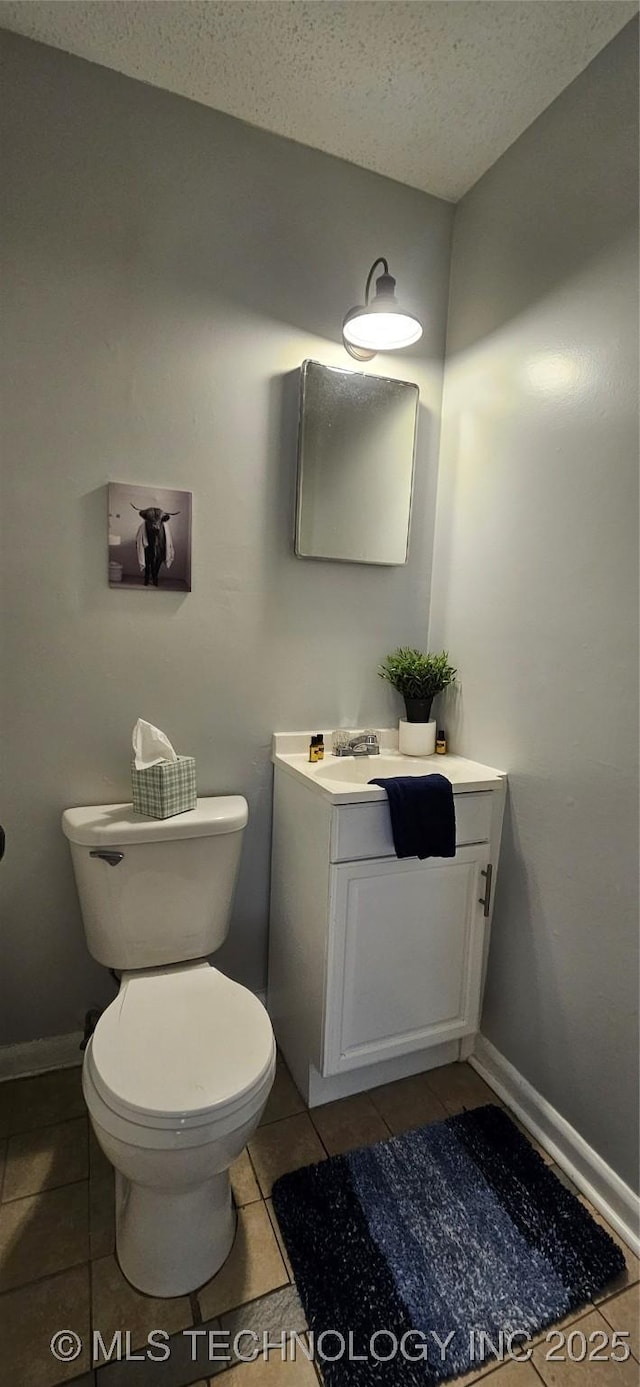 bathroom with toilet, vanity, tile patterned floors, and a textured ceiling