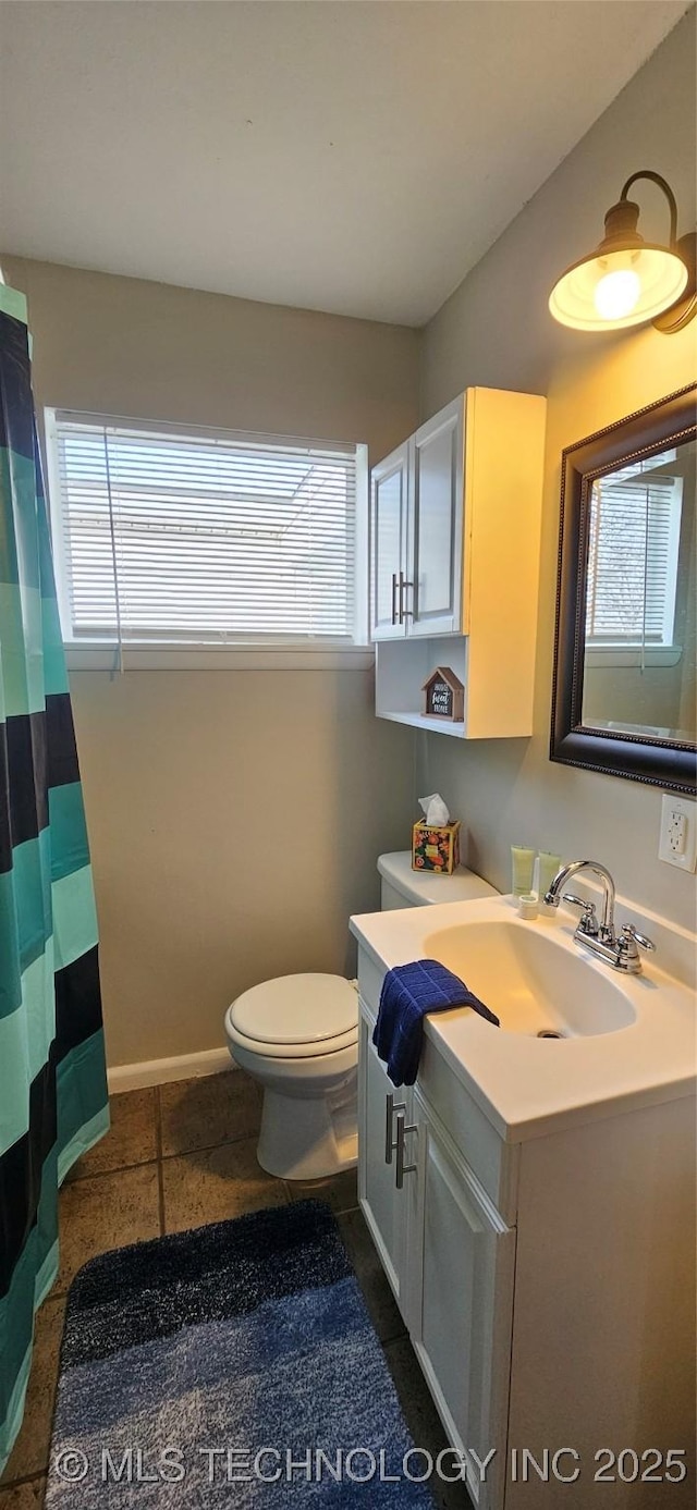 bathroom with toilet, a healthy amount of sunlight, tile patterned flooring, and vanity