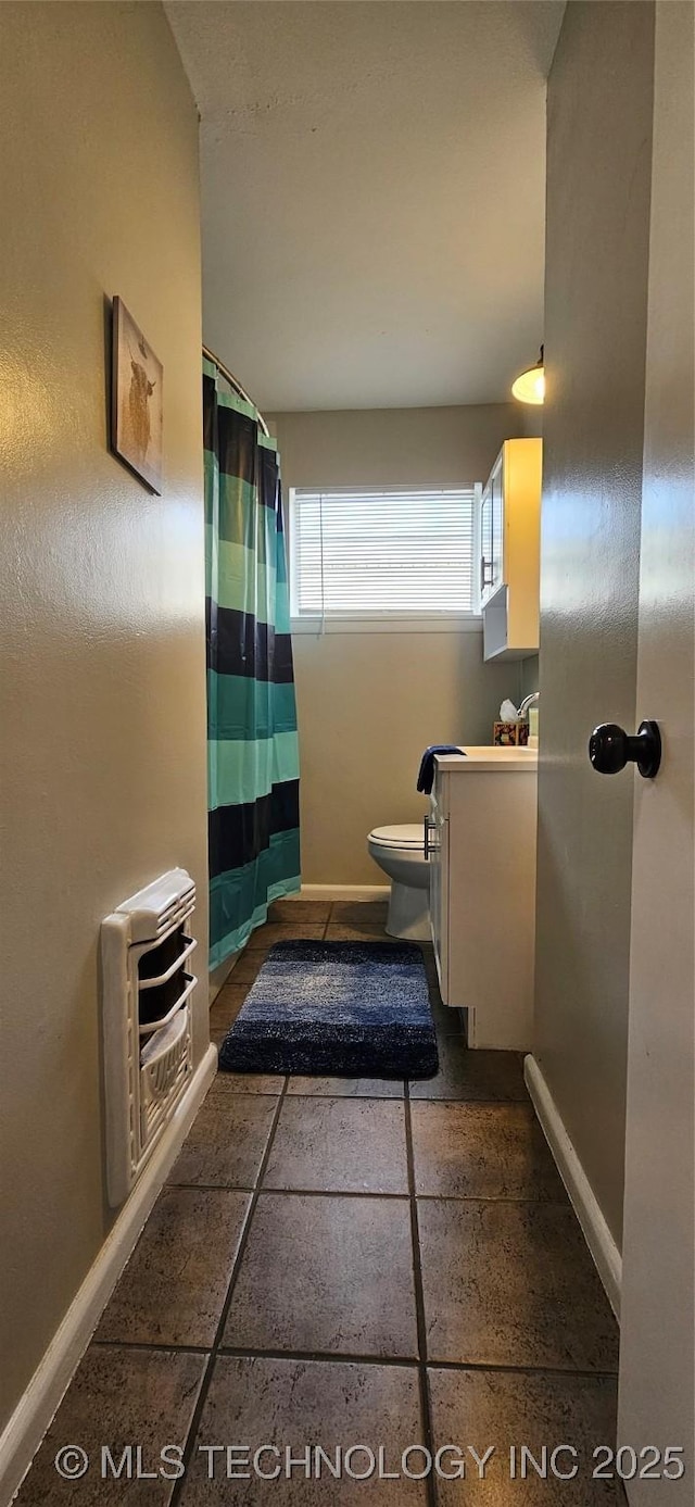 bathroom featuring toilet, heating unit, and vanity