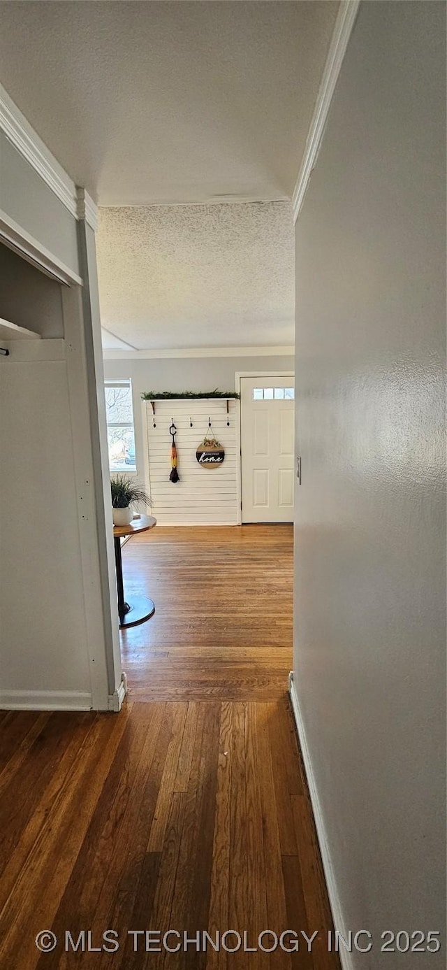 hall featuring hardwood / wood-style floors, ornamental molding, and a textured ceiling