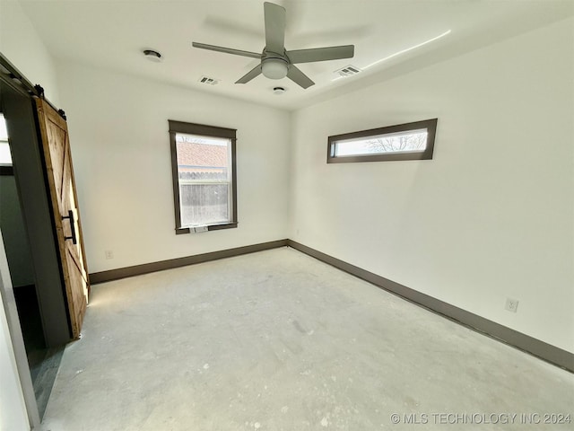 unfurnished room with a barn door and ceiling fan