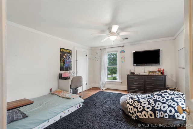 bedroom with light hardwood / wood-style flooring, ceiling fan, and ornamental molding