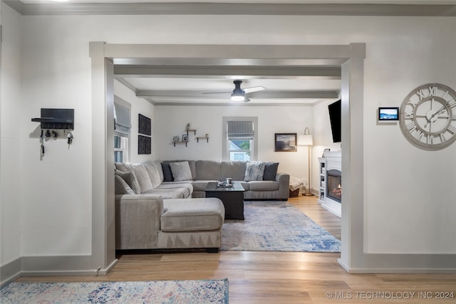 living room with light hardwood / wood-style flooring, ceiling fan, and beamed ceiling