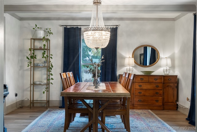 dining area with light wood-type flooring, crown molding, and an inviting chandelier