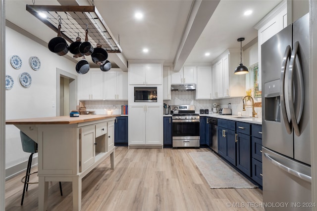 kitchen featuring appliances with stainless steel finishes, hanging light fixtures, white cabinets, blue cabinetry, and light hardwood / wood-style flooring