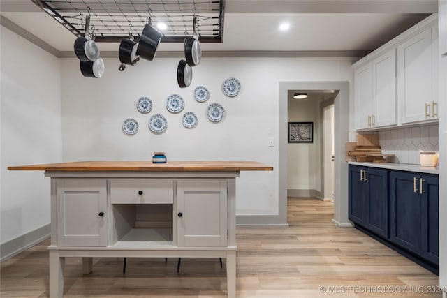 kitchen featuring light wood-type flooring, white cabinetry, decorative backsplash, crown molding, and blue cabinets