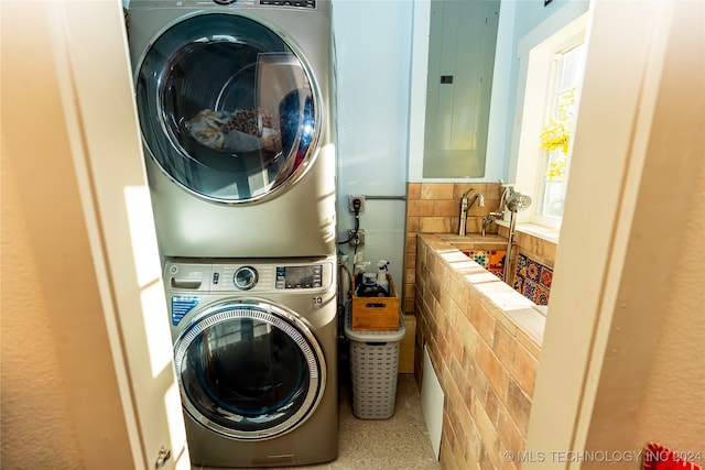 clothes washing area with stacked washer and dryer and electric panel