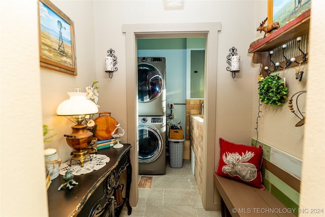 laundry room featuring stacked washing maching and dryer, light tile patterned flooring, and electric panel