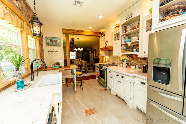 kitchen featuring white cabinets, an inviting chandelier, appliances with stainless steel finishes, decorative light fixtures, and light stone countertops