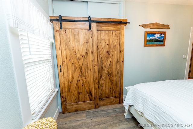 bedroom with wood-type flooring and a barn door