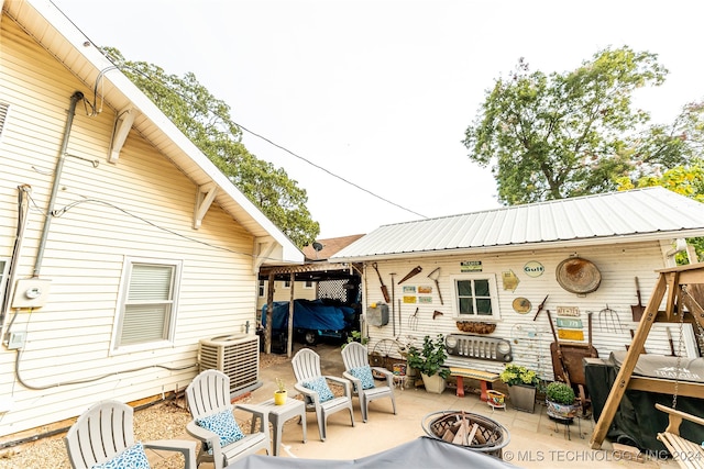 exterior space with cooling unit, a fire pit, and a patio area