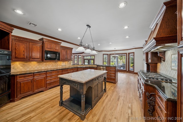 kitchen featuring hanging light fixtures, a kitchen island, light hardwood / wood-style flooring, black appliances, and a breakfast bar area