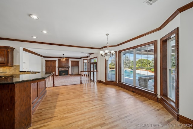 kitchen featuring hanging light fixtures, tasteful backsplash, a chandelier, light wood-type flooring, and crown molding