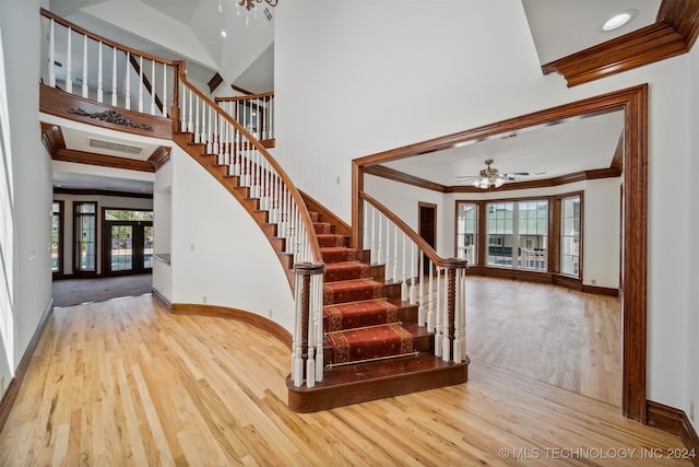 stairway with wood-type flooring, ornamental molding, and ceiling fan