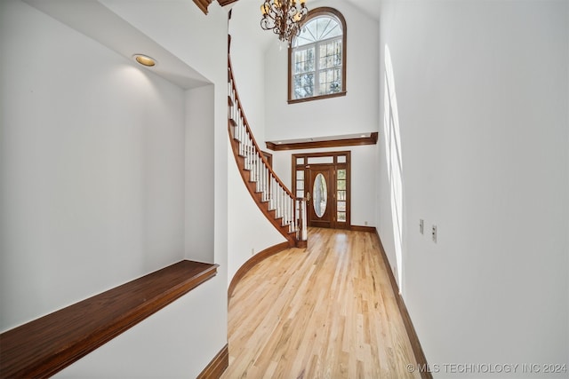 entrance foyer featuring a towering ceiling, a chandelier, light hardwood / wood-style floors, and plenty of natural light