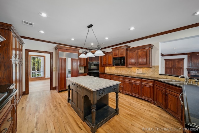 kitchen featuring pendant lighting, sink, a kitchen island, light hardwood / wood-style flooring, and black appliances