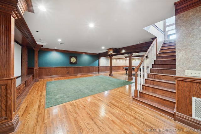 interior space featuring light hardwood / wood-style flooring, wood walls, decorative columns, and crown molding