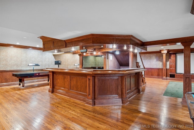 kitchen featuring ornamental molding, a center island, hardwood / wood-style flooring, and ornate columns