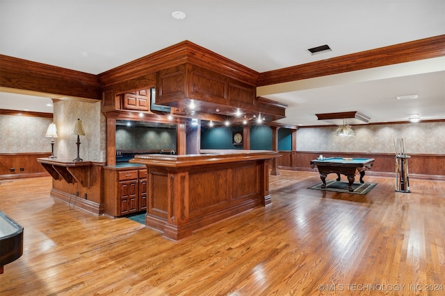 kitchen featuring billiards, a kitchen island, light wood-type flooring, crown molding, and wooden walls