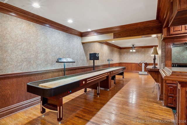 recreation room featuring bar area, ornamental molding, ceiling fan, and light hardwood / wood-style flooring