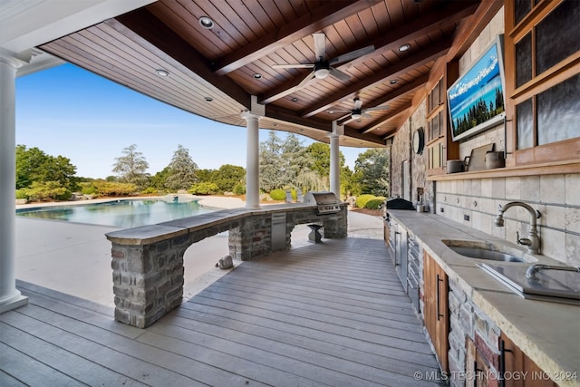 wooden deck featuring area for grilling, sink, ceiling fan, and exterior kitchen