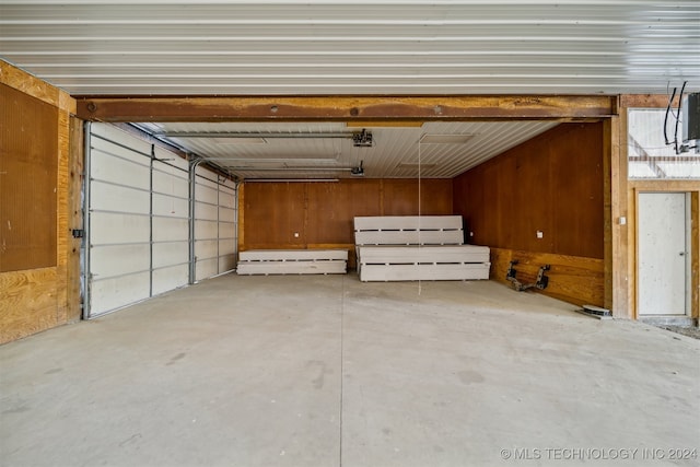 garage with a garage door opener and wood walls