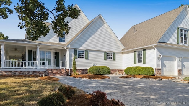 view of front of property with a porch, a garage, and a front lawn