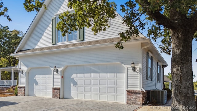 view of side of home featuring central AC unit and a garage