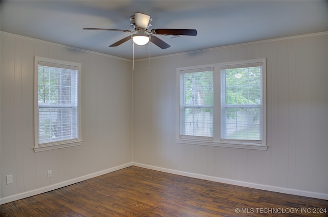 empty room with wood walls, dark hardwood / wood-style floors, ceiling fan, and crown molding