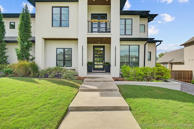 view of front of house with a balcony and a front yard