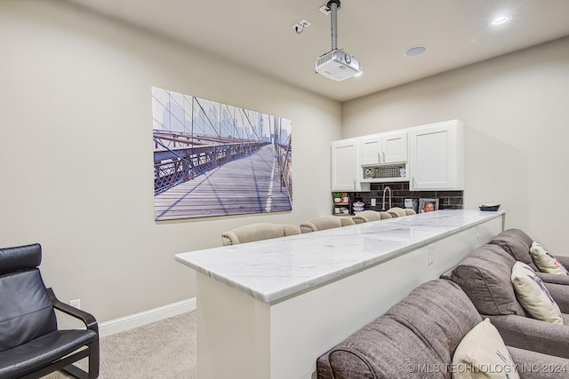 kitchen with white cabinetry, kitchen peninsula, light colored carpet, and decorative light fixtures