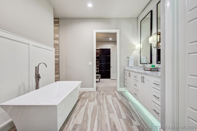 bathroom with wood-type flooring, vanity, and a bathtub