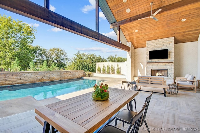 view of swimming pool with an outdoor brick fireplace, a patio area, and ceiling fan