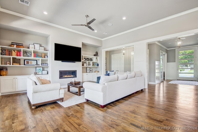 living room featuring ceiling fan, hardwood / wood-style flooring, crown molding, and built in shelves