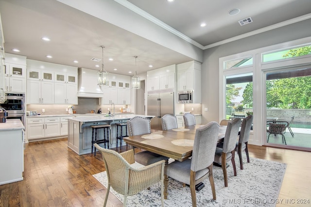 dining area featuring light wood-type flooring, sink, and crown molding