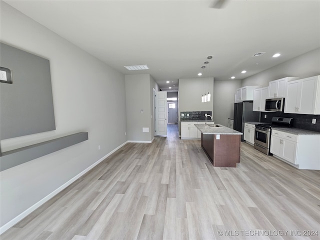 kitchen featuring white cabinetry, stainless steel appliances, light wood-type flooring, a center island with sink, and sink