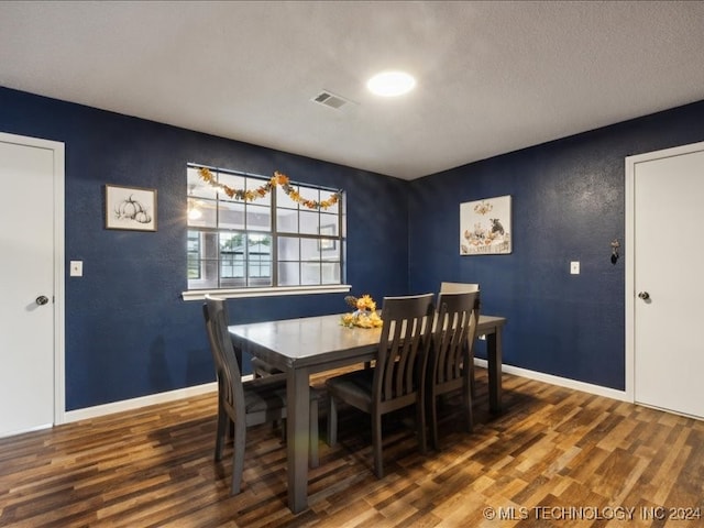 dining room with a textured ceiling and dark wood-type flooring