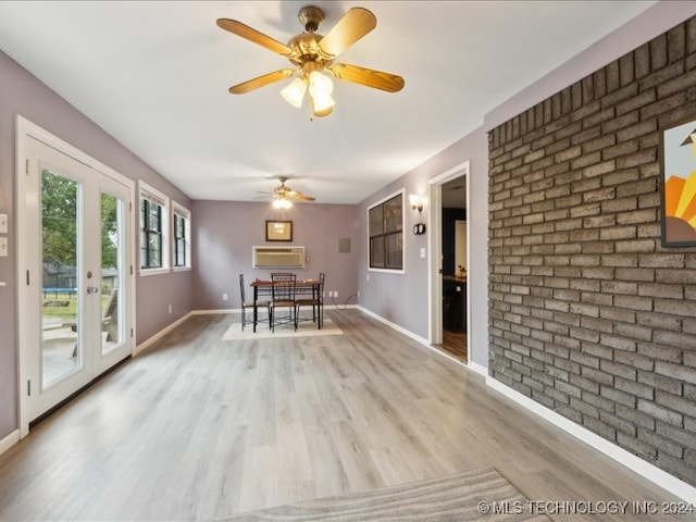 unfurnished dining area featuring ceiling fan, brick wall, french doors, and light hardwood / wood-style floors