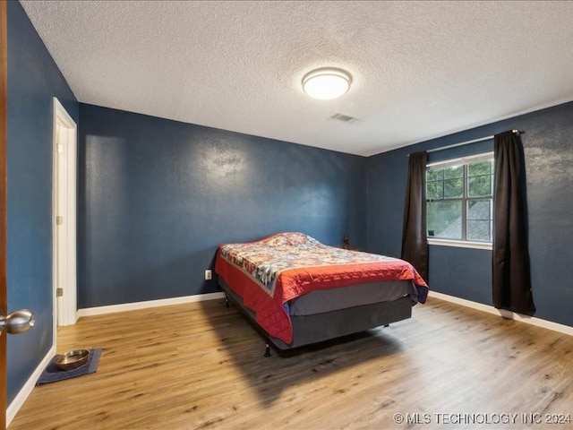 bedroom featuring hardwood / wood-style flooring and a textured ceiling