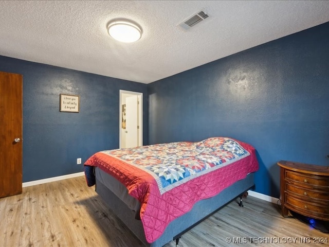 bedroom featuring a textured ceiling and hardwood / wood-style floors