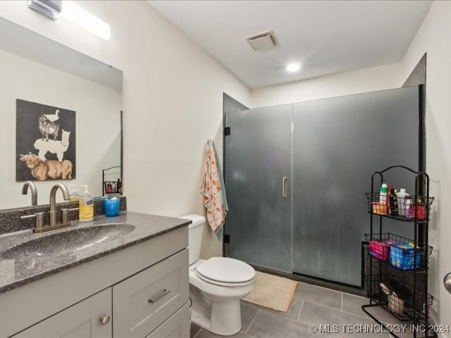 bathroom with vanity, tile patterned flooring, toilet, and a shower with door