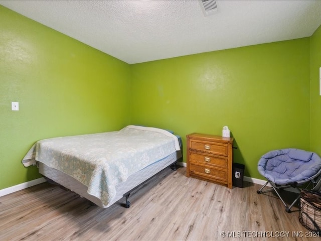 bedroom with light hardwood / wood-style flooring and a textured ceiling